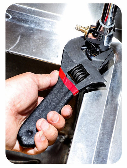 Clé à molette tenue par une main serrant un robinet de cuisine