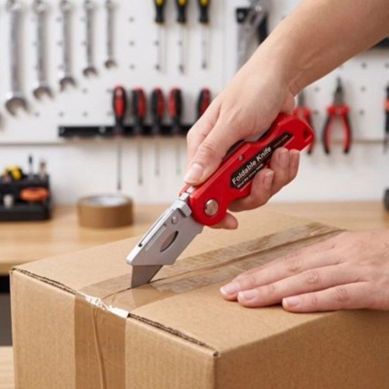 Cutter rouge tenu par une main ouvrant une boite