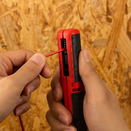 Pince à dénuder et un câble électrique rouge