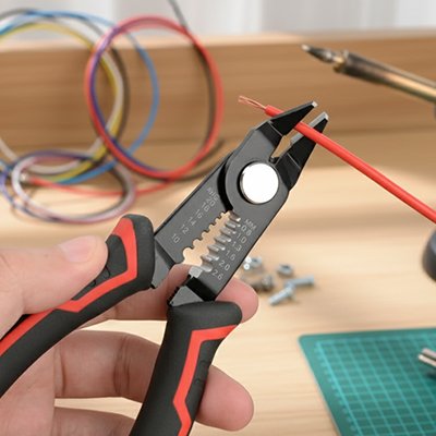 Pince a denuder noir et rouge dénudant un fil électrique rouge