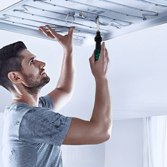 Tournevis dans la main d un homme fixant un panneau de lumière sur un plafond